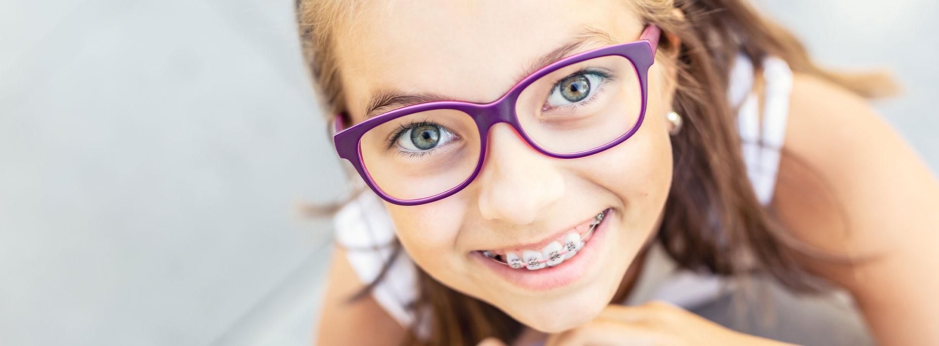A young girl with glasses and braces smiling at the camera.
